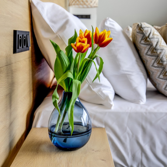 Detail nočního stolku s tulipány u čela postele z dubového dřeva